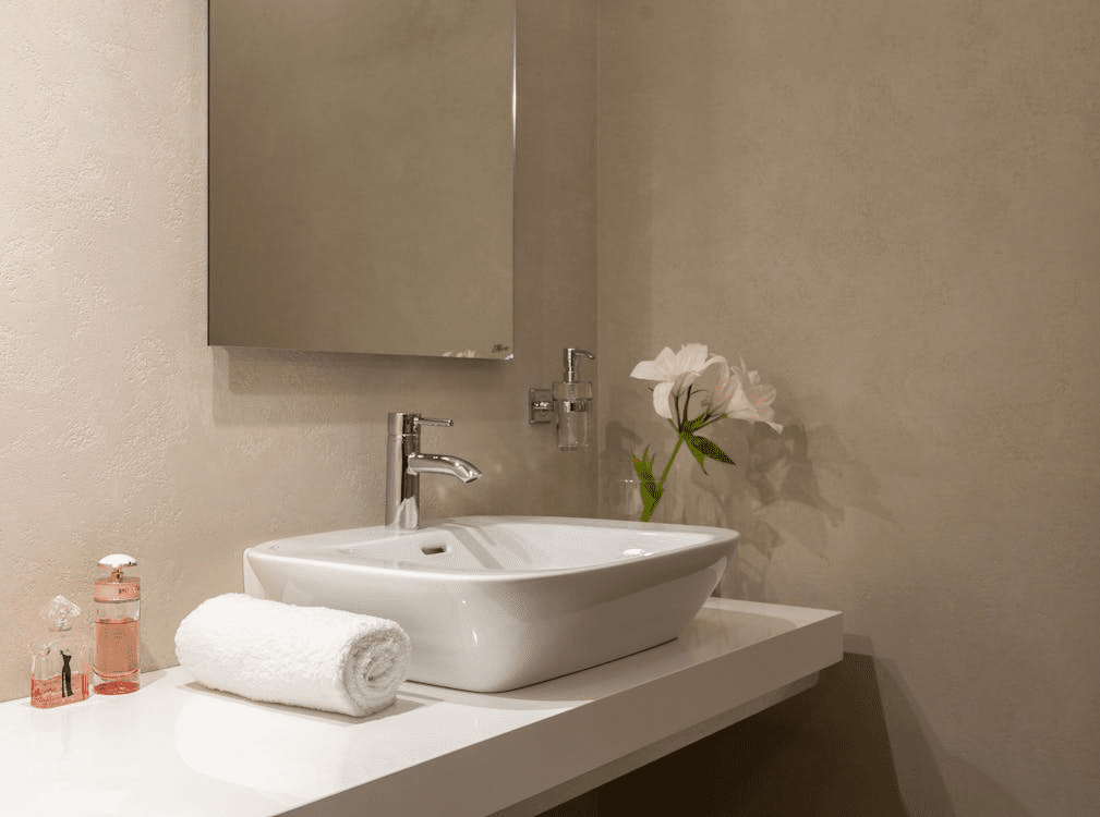 A White Sink And Mirror With A Towel In The Bathroom