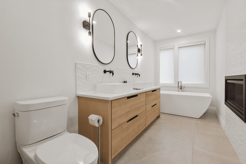 A Contemporary Bathroom With White Fixtures And A Wooden Cabinet